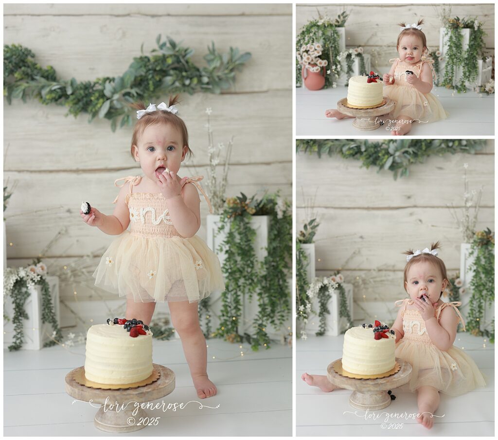 One year old girl first birthday girl cake smash with a cream colored cake with strawberries and blueberries, a Berry Chantilly cake from Whole Foods she is sitting by her cake and eating it