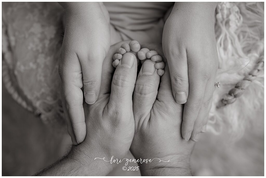 Close-up of newborn baby girl's feet held by mom and dad's hands during professional newborn session by Lehigh Valley photographer Lori Generose in Lehigh Valley, PA – timeless black and white family portrait celebrating new life