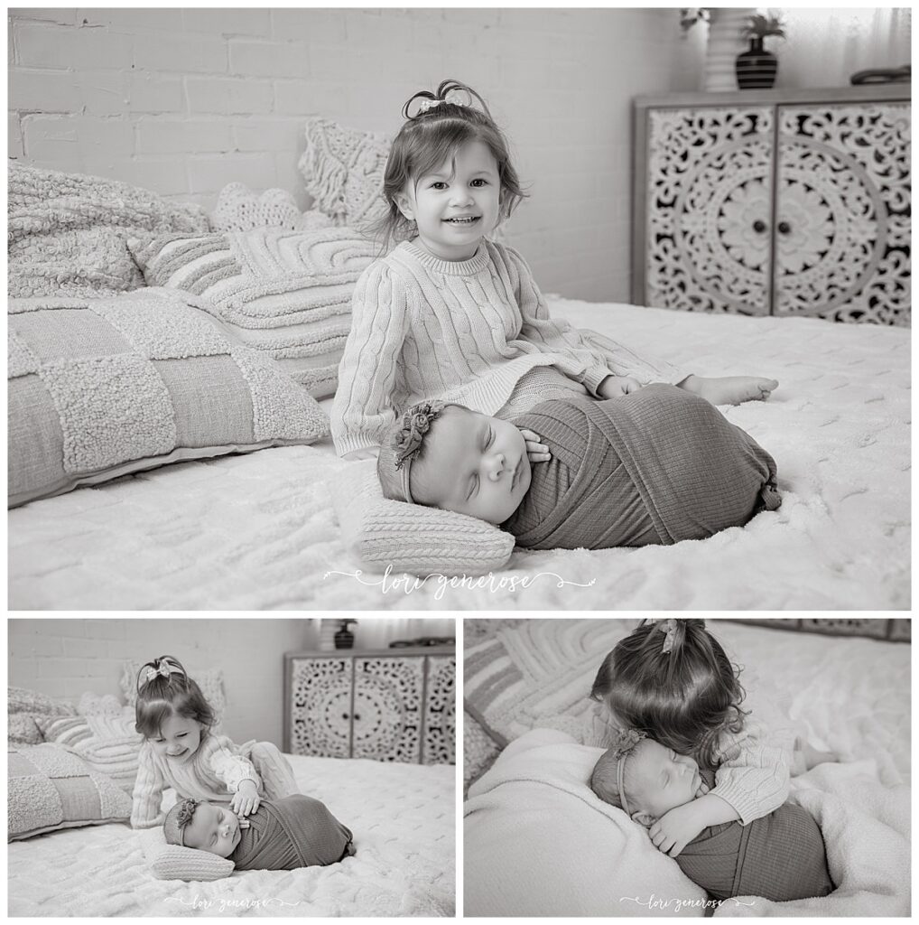 Black and white sister pictures with toddler sister wearing all cream and a newborn baby girl with a sage green wrap snuggling together on a neutral bed set for lifestyle newborn sibling photos by Lehigh Valley newborn photographer Lori Generose of LG Photography