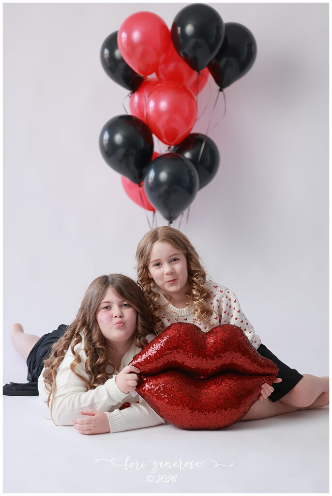 Valentine's Day photo by Lehigh Valley Photographer Lori Generose of LG Photography of two little girls giving kissy faces with a big sequin lips pillow