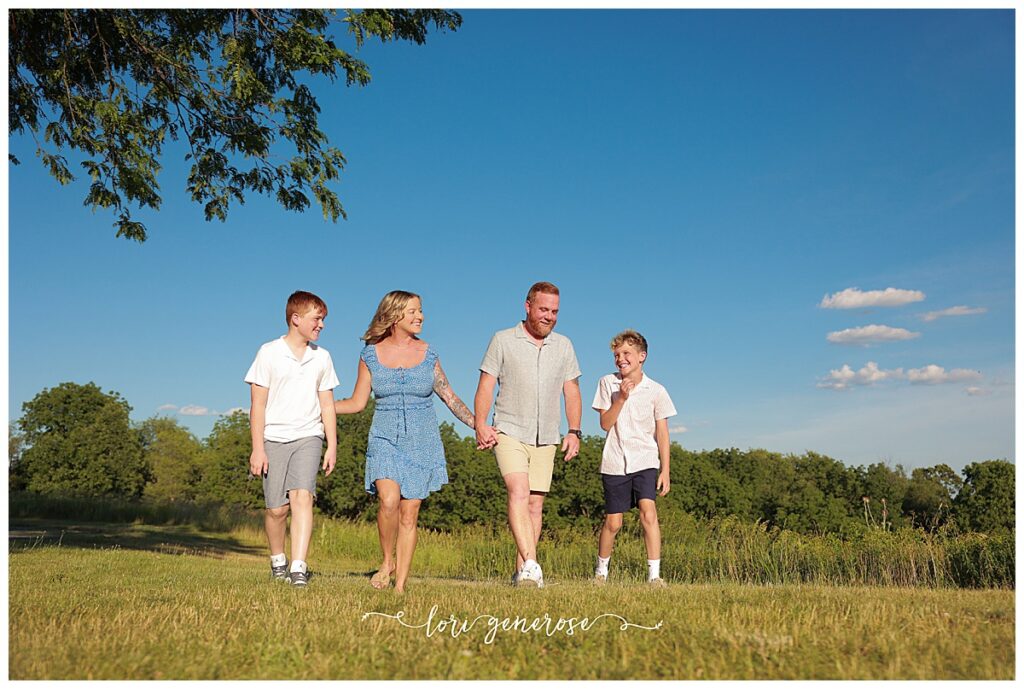 Family photoshoot of mom, dad and their two boys ages 11 and 13 in tall green grasses with gorgeous light at Trexler Nature Preserve in Schnecksville, PA by Lehigh Valley Photographer, Lori Generose of LG Photography
